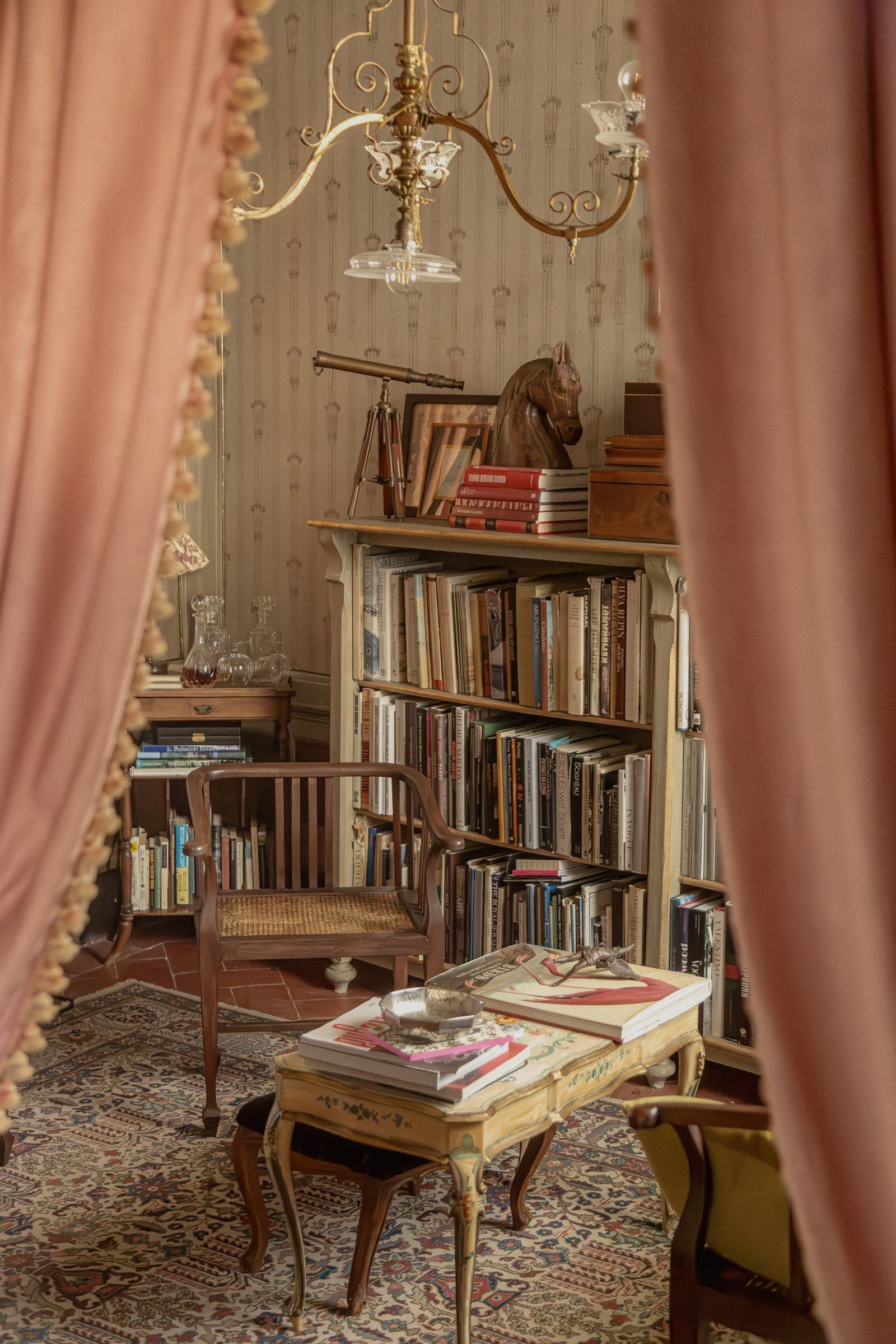 A library framed by soft pink curtains at Locanda Sospesa.