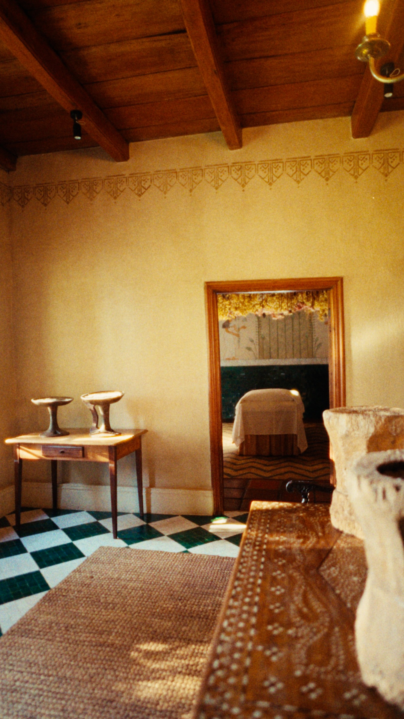 A sunlit bathroom with checkerboard tiles and painted walls.