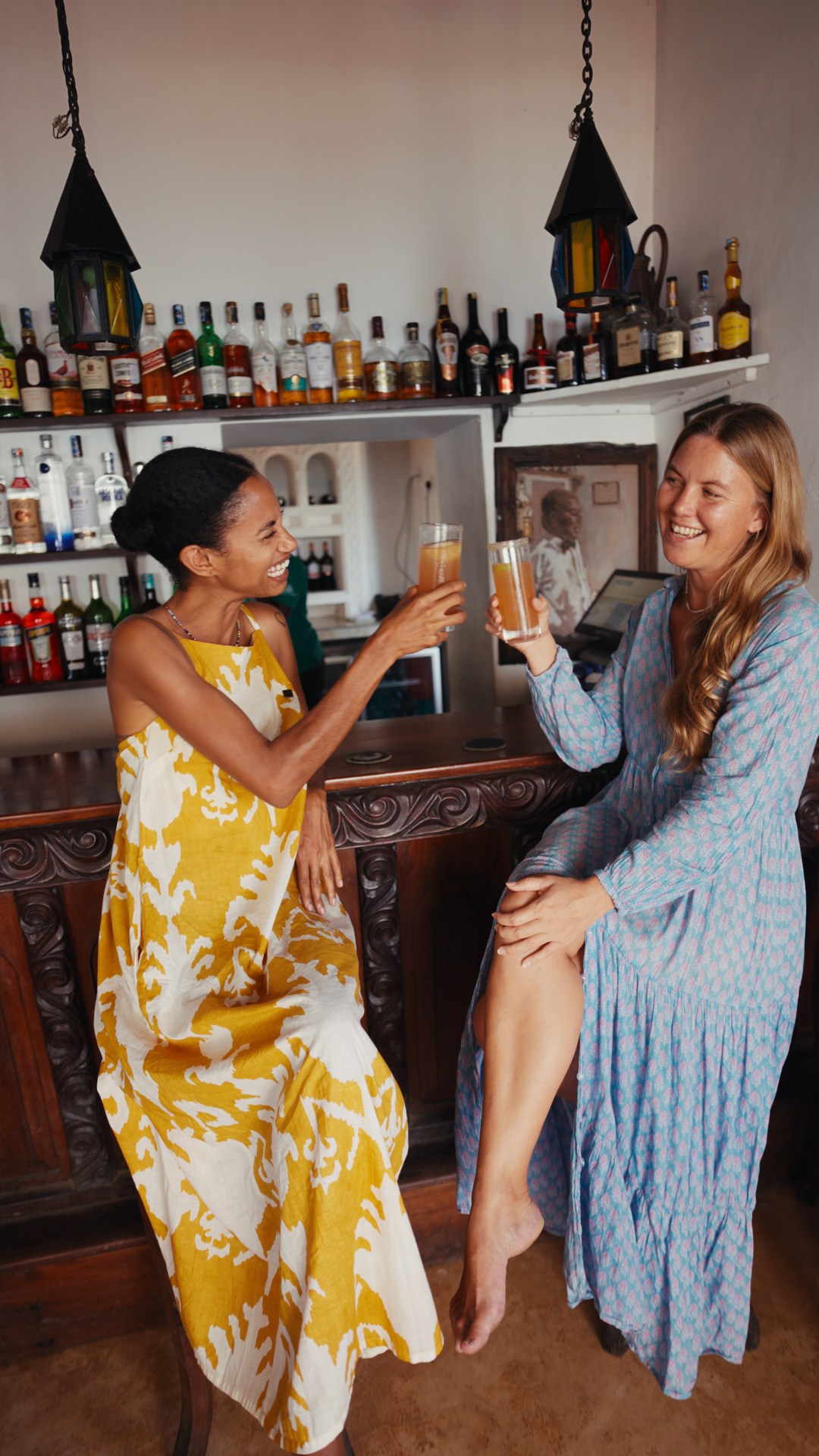 Yaye and Elke laughing and raising their drinks at Peponi’s bar