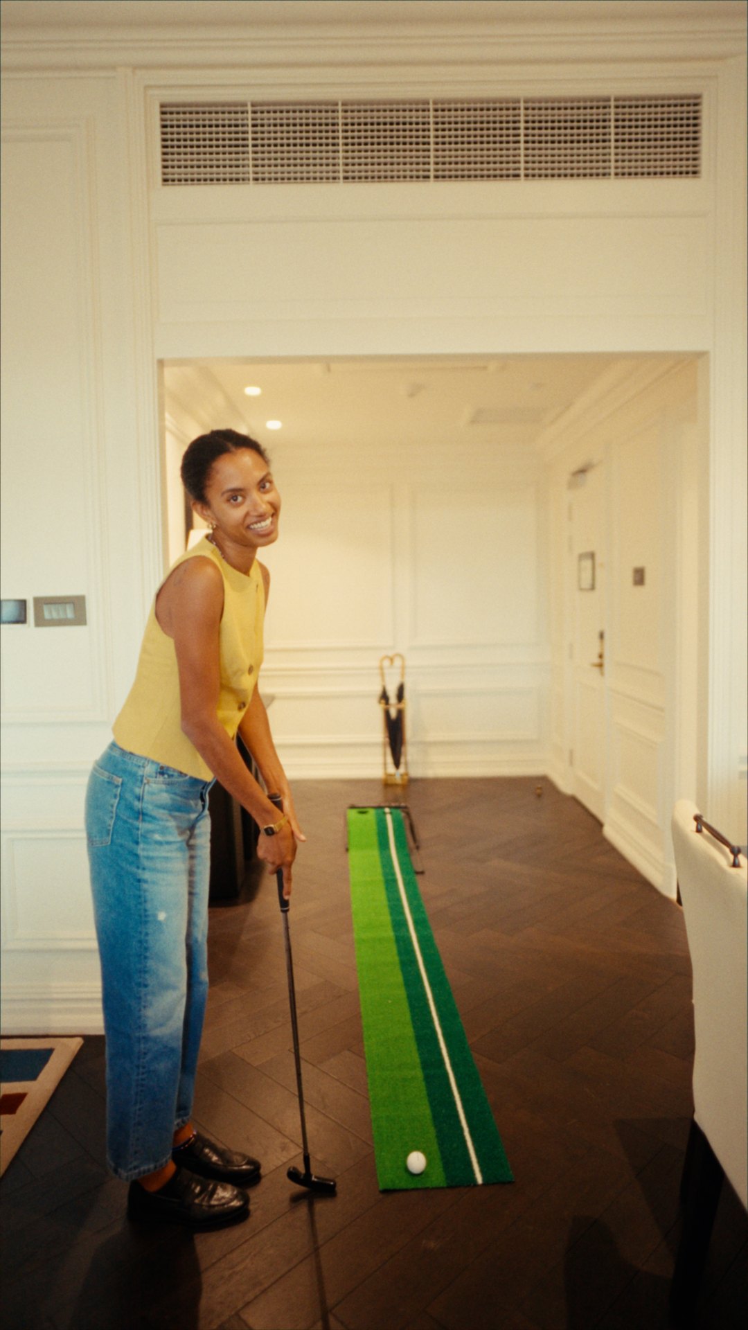 Yaye playing with an indoor putting mat in her Cape Grace suite